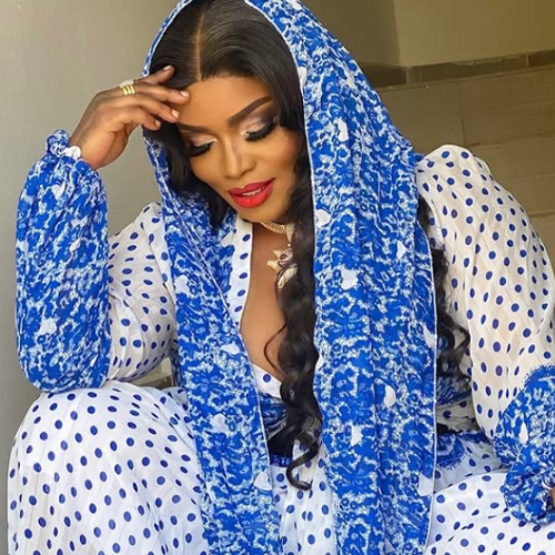Picture of actress Halima Abubakar wearing a blue patterned dress in a pose with her right hand on forehead