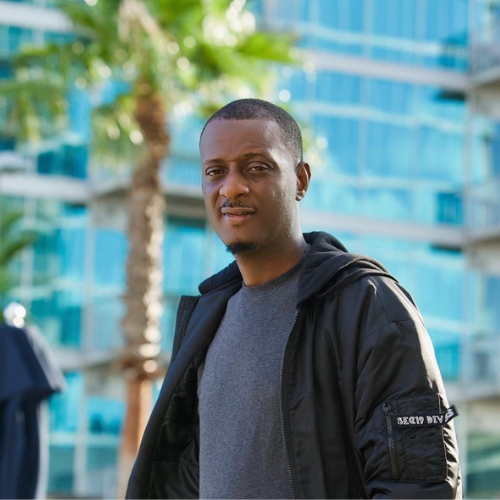 Picture of ID Cabasa wearing a hooded jacket, hoody slouched to back, and Charcoal grey t.shirt