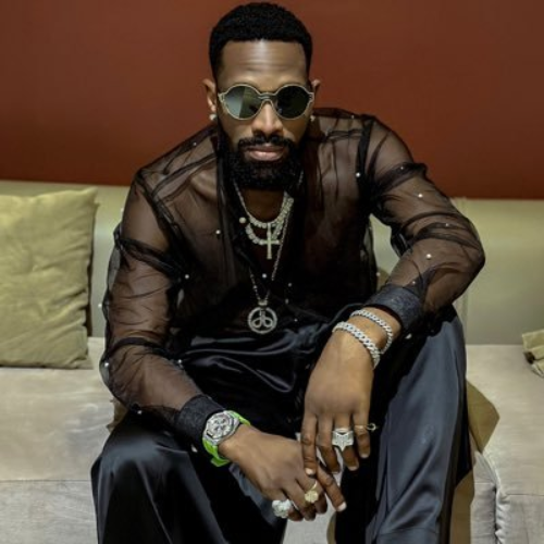 D'banj, honored by Rema, stuns in a sheer silk shirt paired with dazzling diamond-encrusted jewelry and sleek chrome shades.